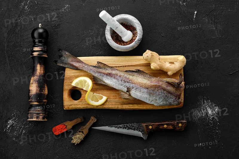 Raw fresh frozen pollock carcass with spices on cutting board