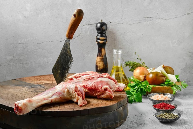 Raw lamb shoulder half cut on wooden slab