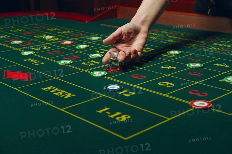 Casino roulette table with chips and cards. Winning combination. Hand of Croupier behind gambling table