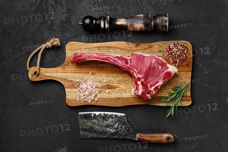 Top view of raw prime ribeye steak on wooden cutting board