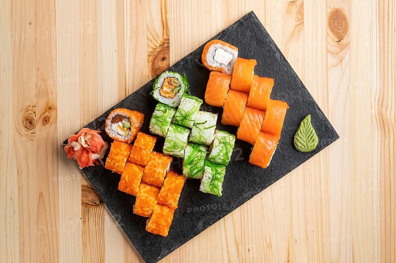 Set of rolls with wasabi and pickled ginger on stone serving board