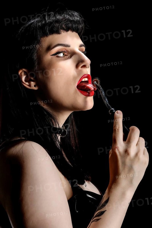 Woman with Wartenbergrad on her tongue in vinyl and latex outfit
