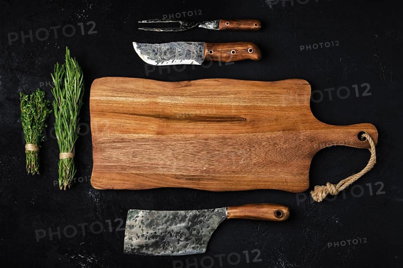 Top view of wooden cutting board with butcher tools
