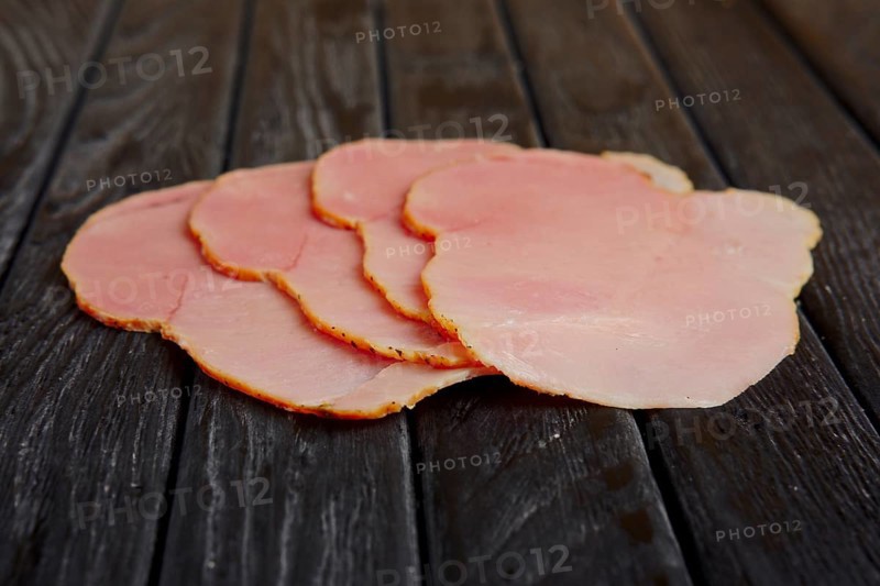 Selective focus photo of slices of fresh ham on wooden table