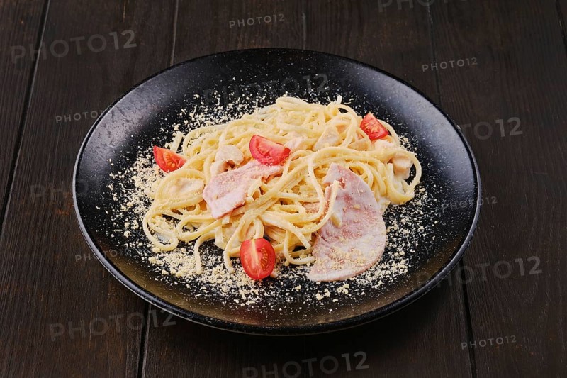 Spaghetti with ham and tomatoes sprinkled with grated parmesan