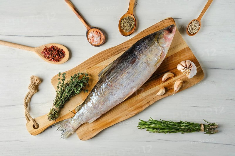 Overhead view of raw frozen unpeeled omul on wooden cutting board
