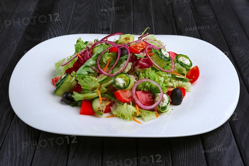 Salad with feta cheese rolled in cucumber slices with tomato and red onion
