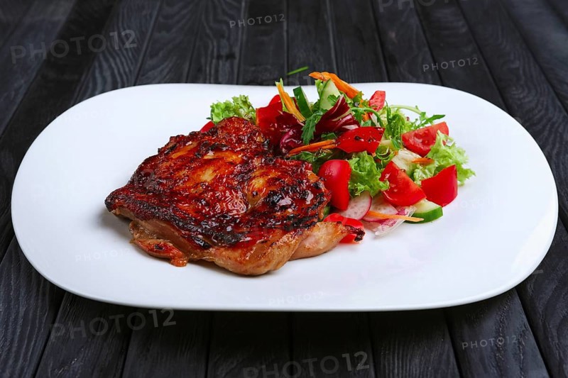 Juicy and crispy chopped pork fried on grill with fresh vegetables