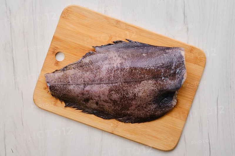 Top view of raw fresh halibut without head on wooden cutting board