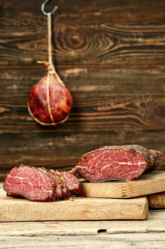 Smoked dried beef meat cut on slices on wooden cutting board