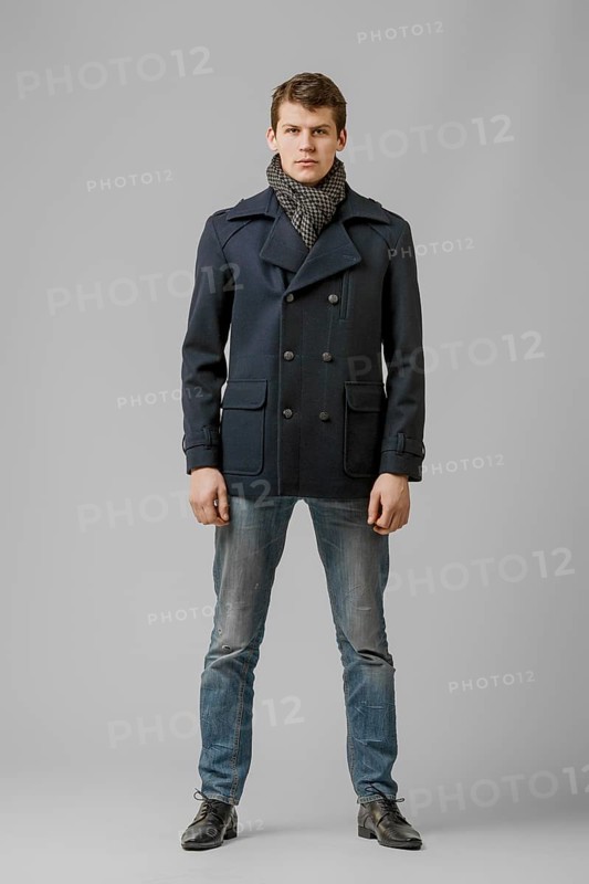 Full length portrait of handsome man in warm woolen coat posing in studio
