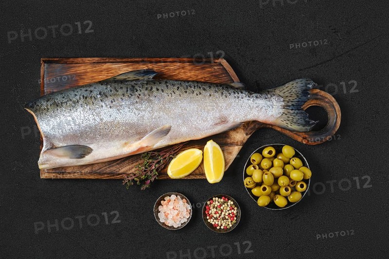 Headless fresh chinook on wooden cutting board with spice and lemon