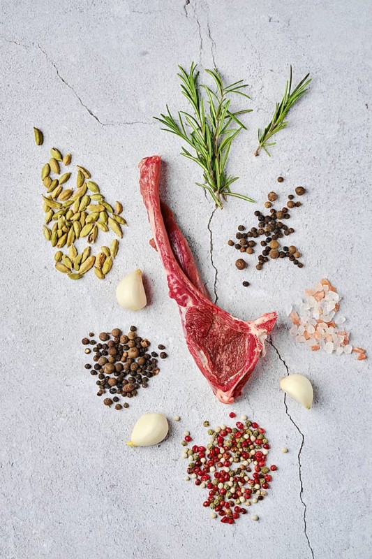 Composition with raw doe ribs with spice and herb over concrete background