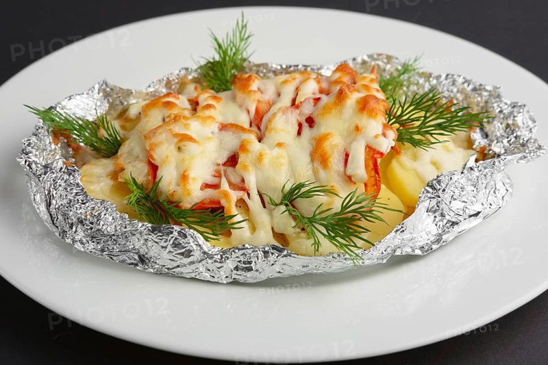 Closeup view of fried in foil sea fish and potato with paprika and cheese