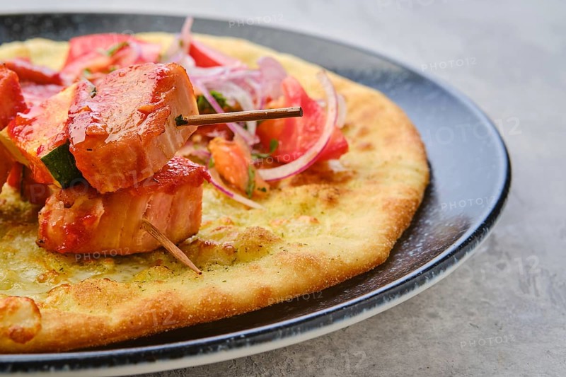 Closeup view of shashlik served on tortilla with tomato and red onion