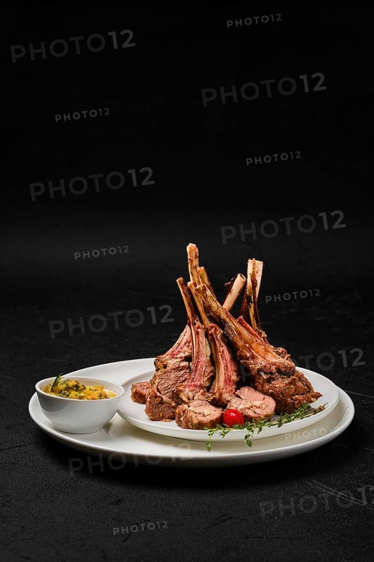 Grilled rack of lamb on a plate with spicy sauce