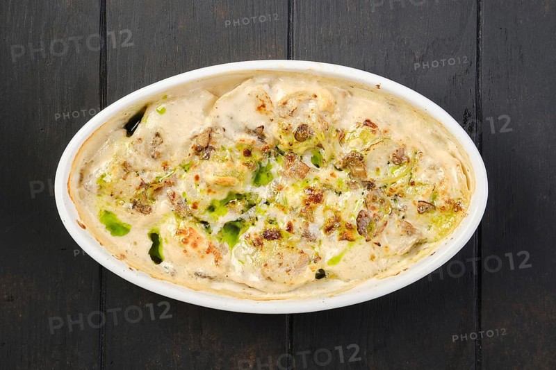 Overhead view of chicken dumplings with spicy onion sauce baked in oven
