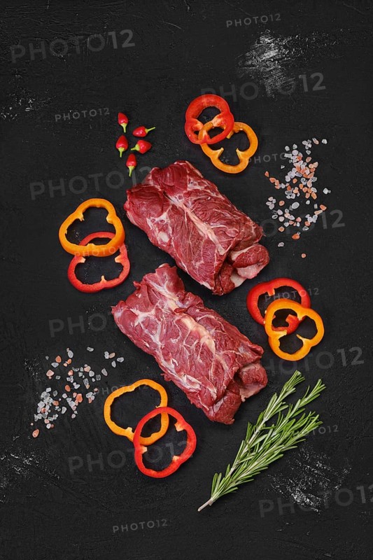 Overhead view of raw fresh lamb neck meat with slices of bell pepper