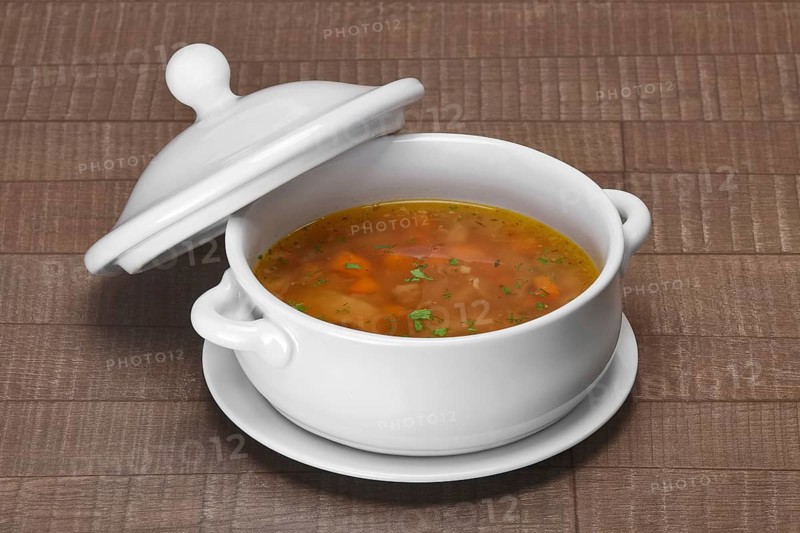 Portion of cabbage soup in ceramic pot on wooden table
