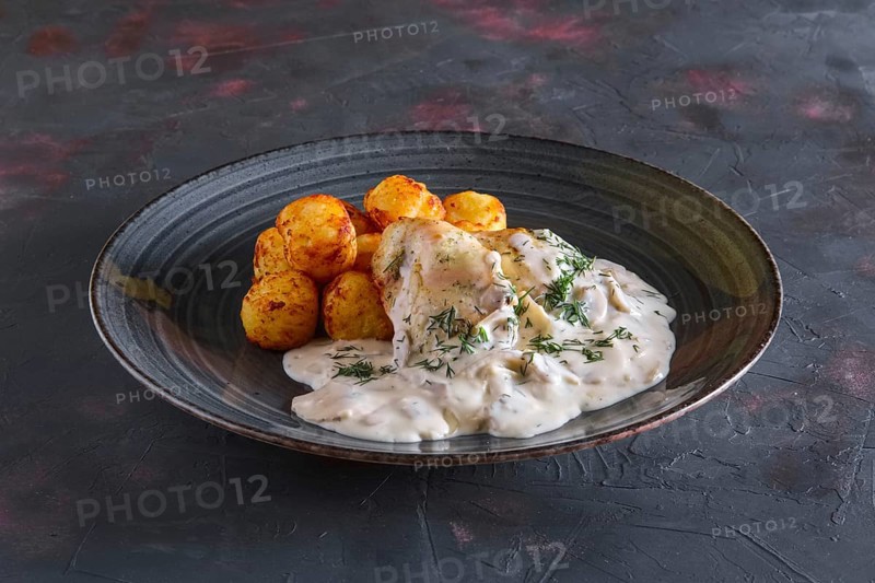 Fried potato balls and white fish fillet with creamy sauce
