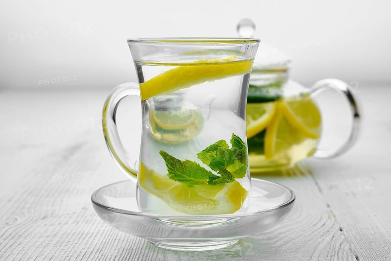 Antioxidant hot drink with lemon and mint in transparent tea pot and glass
