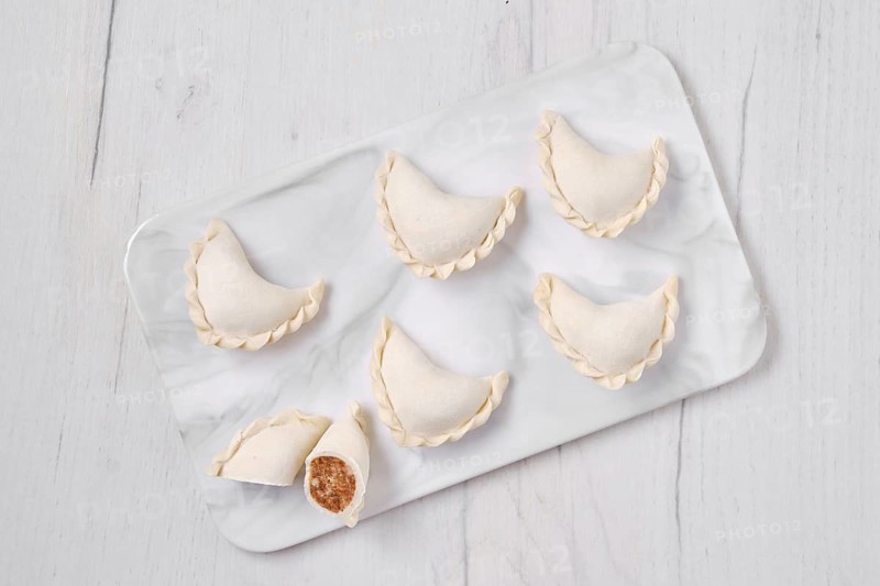 Top view of frozen dumplings stuffed with beef meat and provencal herbs on marble serving plate