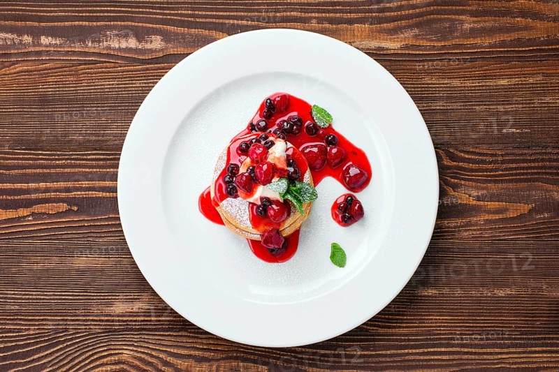 Overhead view of american pancakes with strawberry and black currant jam
