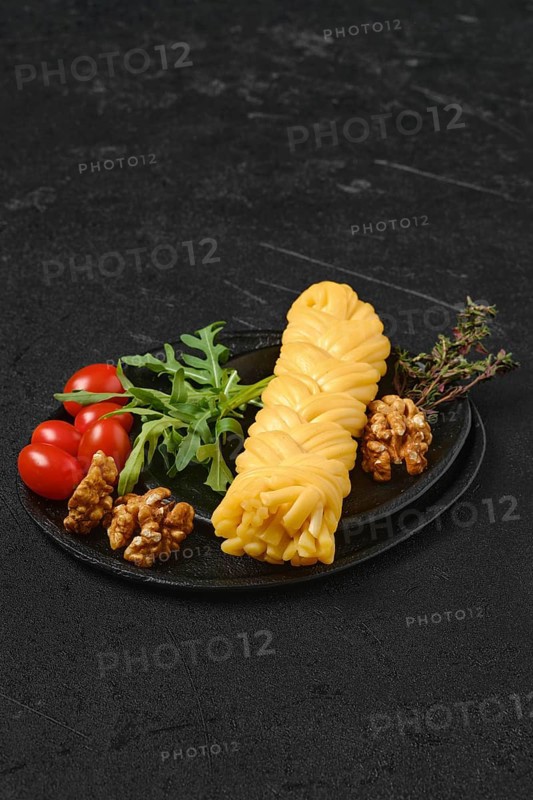 Smoked braided cheese with walnuts and tomatoes on a plate