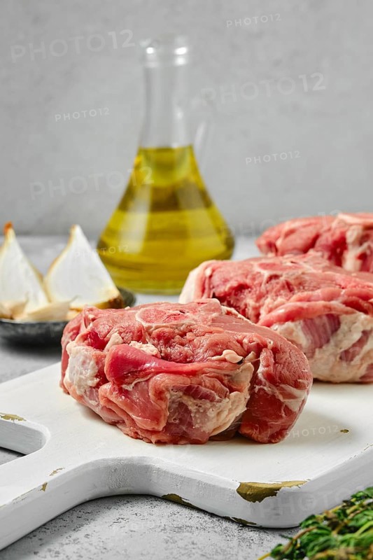 Uncooked raw lamb loin chops saddle steaks on wooden cutting board