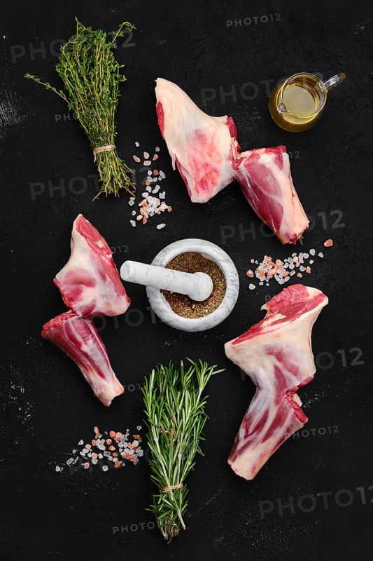 Fresh raw lamb ram shank with spice and herbs on dark background