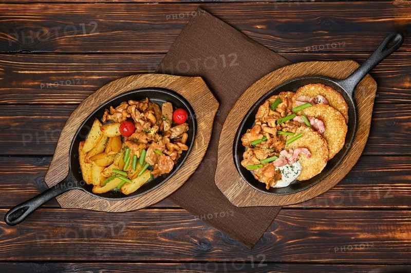 Top view of potato wedges with chanterelles and pork in cast iron skillet