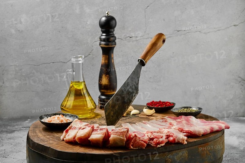 Raw fresh lamb flap ribs with ingredients for cooking on wooden log