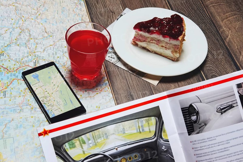 Cup of fruit-drink near map and smartphone with magazine on the table. Top point of view