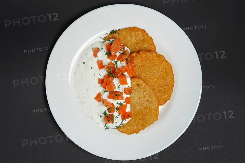Top view of traditional belorussian potato pancakes with salmon and sour cream