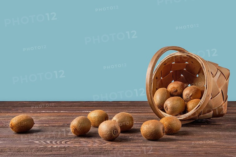 Basket with fresh kiwi on wooden table