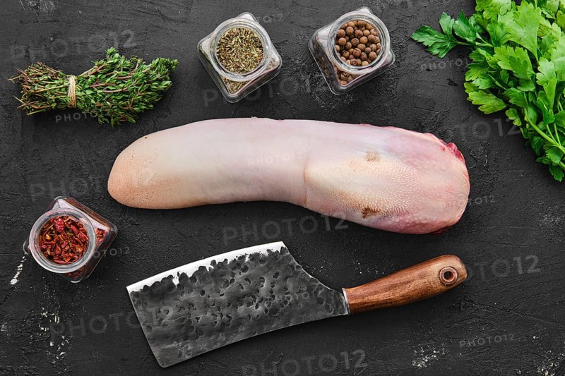 Raw fresh beef tongue with spice and herbs on black background