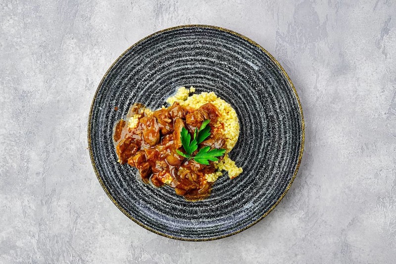 Top view of beef goulash with millet porridge and creamy sauce