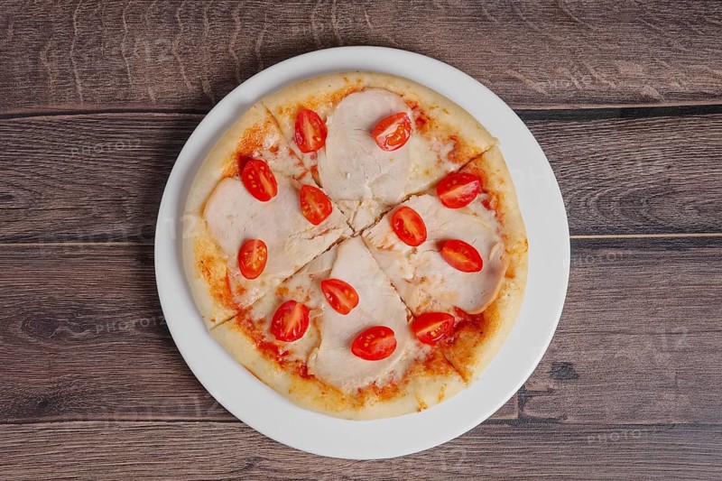 Pizza with ham and tomato on wooden table
