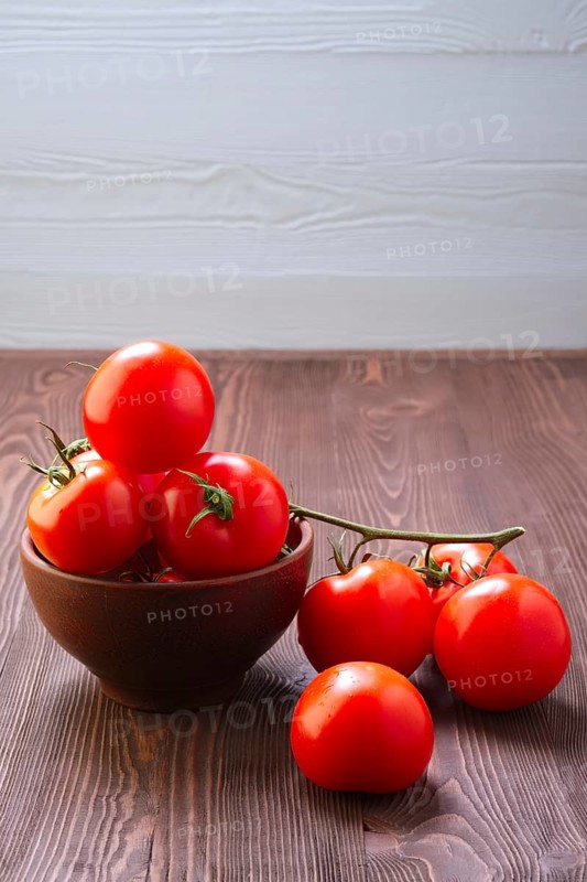 Branch of fresh tomatoes on wooden table