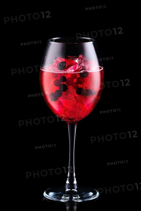 Cold sangria with forrest berries in a wine glass isolated on black background