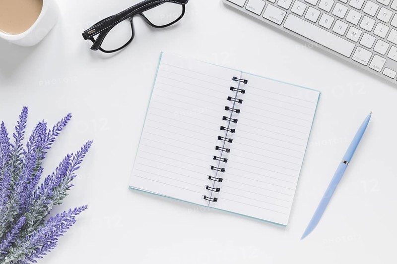 Opened notebook near lavender keyboard glasses desk