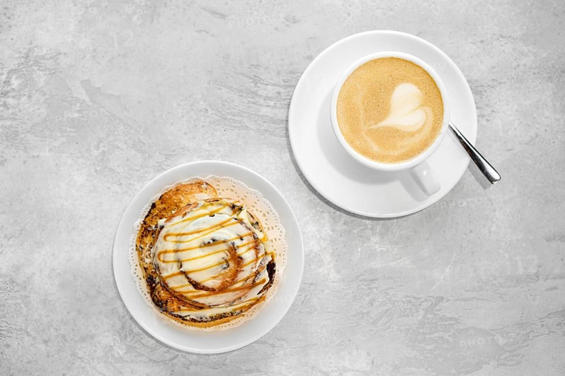 Cappuccino and rolled bun with caramel on a table