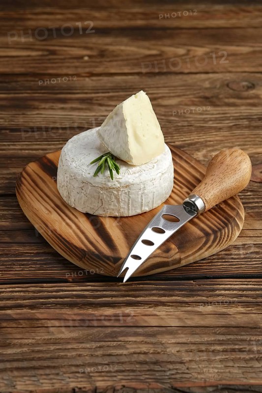 Brie cheese or camembert on woden board with knife for soft cheese