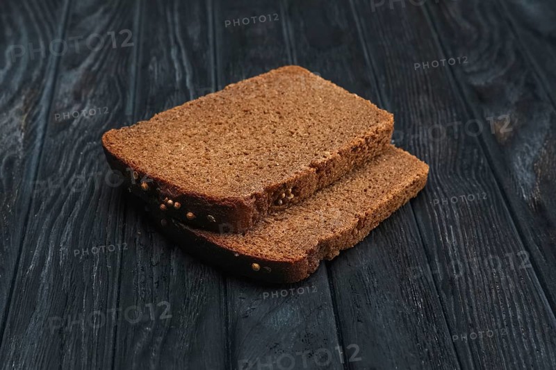 Two pieces of brown bread on dark wooden table