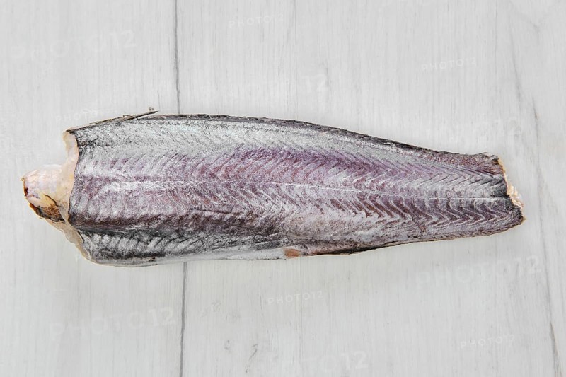 Frozen raw hake carcass on wooden table
