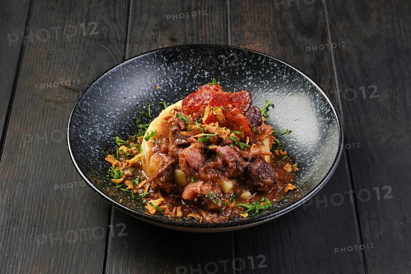 Beef goulash with bacon and mashed potato on a table