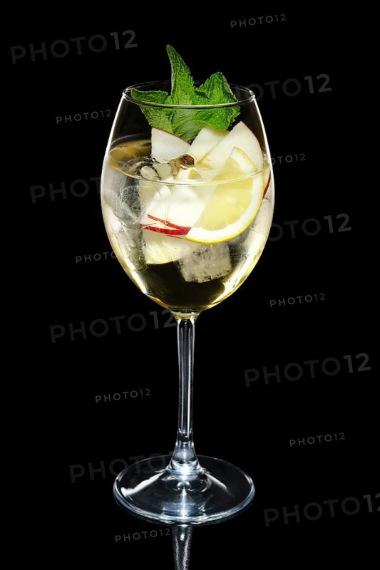 Apple cocktail with a sparkling wine with ice cubes in wine glass isolated on black