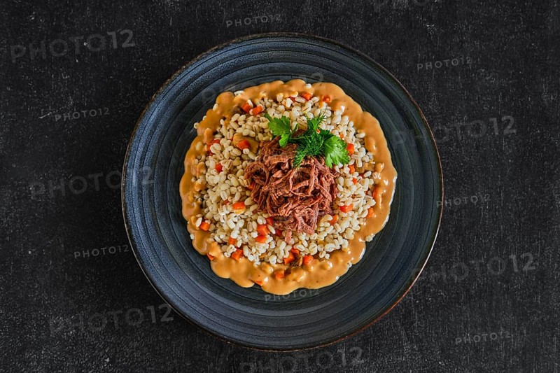 Top view of pulled beef with pearl barley and creamy sauce