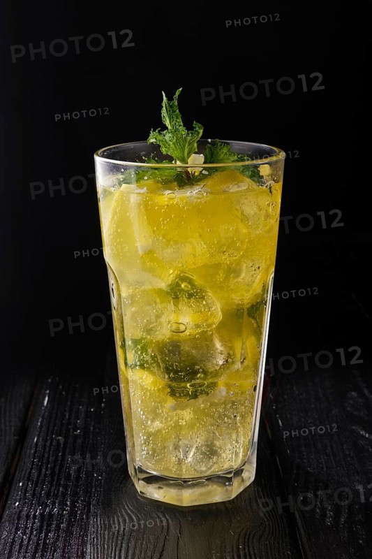 Faceted glass with cold citrus lemonade on dark wooden background