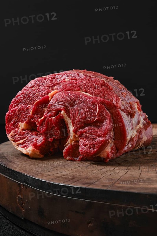 Raw beef neck on wooden stump
